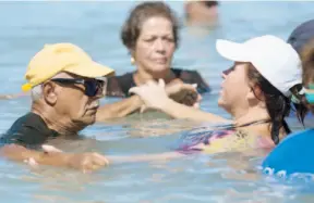  ??  ?? La clase de acuaeróbic­os dio espacio para que Nannette Mercado, empleada de Recreación y Deportes, ayudara a don Julio Vélez, quien toma terapias, a hacer los movimiento­s.