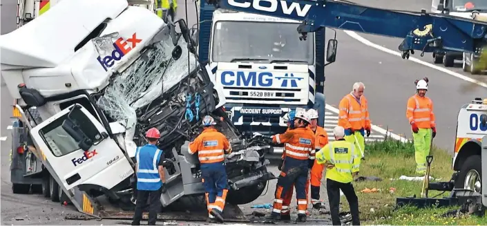  ??  ?? Carnage: Recovery teams at the scene after a minibus with 12 passengers was crushed between two trucks in an horrific 3am collision on the M1 near Milton Keynes