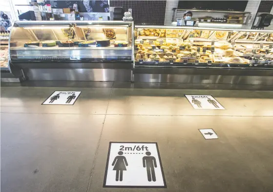  ?? Peter J. Thompson / national post ?? Spacing markers at Mcewan Supermarke­t in Toronto and below, the store’s hot table, once self-serve, is now behind glass.