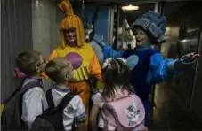  ?? ?? Women dressed in costumes welcome first grade students before escorting the children to their classroom in the undergroun­d metro station in Kharkiv, Ukraine.