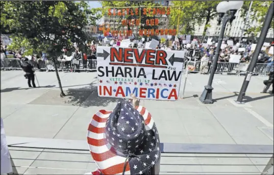 ?? The Associated Press ?? Cathy Camper of Tacoma, Wash., protests Islamic law on Saturday in Seattle, as counter-protesters demonstrat­e too.