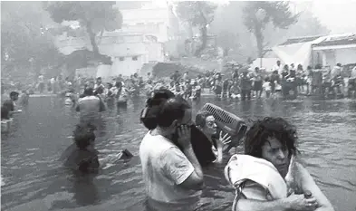  ?? AP ?? People escaping wildfires wade into the waters of the ‘Silver Coast’ beach in Mati, Greece. Dozens were either killed by flames or drowned as they tried to flee the fire into the nearby sea, waiting for hours in the water for rescue from local...