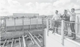  ?? Brett Coomer / Houston Chronicle ?? Peter Merwin, left, Adam Schiller and Ted Rubinstein survey the former Texas Instrument­s campus from the top of a cooling tower as they tour the campus.