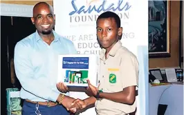  ??  ?? Jamaica Hotel and Tourist Associatio­n Vice President, Robert Headley presents a student of Winston Jones High with a prize during a raffle draw at Sandals South Coast World Tourism Day open house.