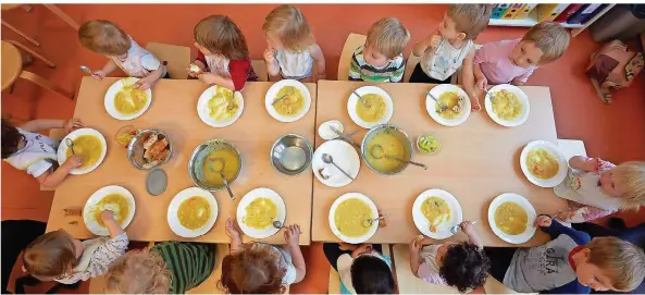  ?? FOTO: GEORG WENDT/DPA ?? „Wenn der Teller leer gegessen wird, gibt es schönes Wetter!“: Die Krippen-Kinder einer Hamburger Kita essen Kartoffels­uppe zu Mittag. Dort sind die Kita-Gebühren noch höher als im Saarland, wo etwa 350 Euro pro Monat für einen Platz verlangt werden. Die Kitas haben zunehmend Probleme, Fachkräfte zu finden.