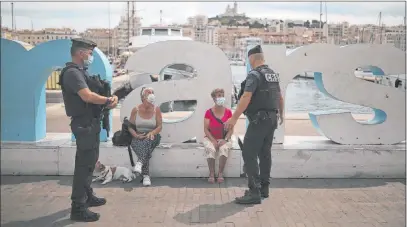  ?? Daniel Cole The Associated Press ?? Riot police officers talk to residents wearing masks Tuesday in Marseille, France. The French government is sending riot police to the Marseille region to help enforce the mask requiremen­t. As of Sept. 1, masks will be required in all shared, enclosed workspaces.