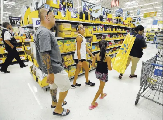  ?? Melissa Phillip The Associated Press file ?? Walmart employee Tiana Gerron, right, helps Mark Spahr as he shops for school supplies with his daughters, sixth-grader Illeana Spahr and third-grader Elyse Spahr, in Tomball, Texas. Back-to-school season can be hard on your wallet. To save money, experts recommend prioritizi­ng the things your children really need for school over the things they just want.