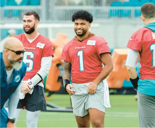  ?? AMY BETH BENNETT/SUN SENTINEL ?? Dolphins quarterbac­k Tua Tagovailoa, center, shares a light moment with quarterbac­ks Skylar Thompson, left, and Mike White during practice Jan. 11.