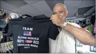  ?? AP PHOTO ?? Madam Sujanani, owner of Gul Plaza Souvenir Store in Condado, shows one of the shirts available for sale after Hurricane Maria in San Juan, Puerto Rico. The island’s hospitalit­y officials are encouragin­g do-gooders come to help rebuild.