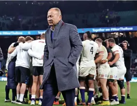  ?? ?? Eddie Jones, the England head coach, walks off the pitch after the draw with the All Blacks as England’s players remain in a team huddle