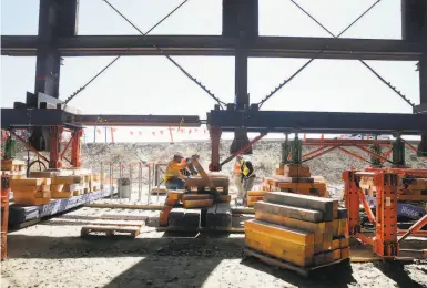  ?? Paul Chinn / The Chronicle ?? Constructi­on workers slip boards beneath a hydraulic jack that is being used to lift Building 12, inches at a time, as part of the Pier 70 redevelopm­ent project on San Francisco’s southeast waterfront.