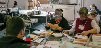  ?? — AFP photo ?? Election workers sort absentee ballot envelopes at the Lansing City Clerk’s office in Lansing, Michigan.