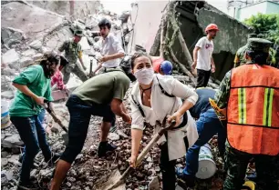  ?? —AFP ?? Rescuers, firefighte­rs, policemen, soldiers and volunteers remove debris from a flattened building in search of survivors in Mexico City.