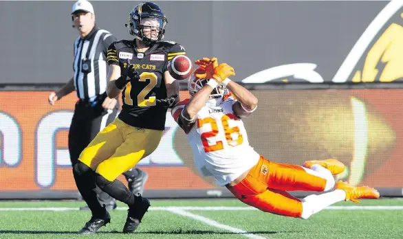  ?? PETER POWER/THE CANADIAN PRESS ?? B.C. Lions defensive back Anthony Orange couldn’t close his hands on the ball but Hamilton Tiger-Cats receiver Mike Jones could Saturday in Hamilton.