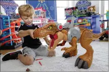  ?? RICHARD DREW / ASSOCIATED PRESS ?? Five-year-old Alexander explores a Jurassic World Jurassic Rex at a Walmart Toy Shop event in New York. “When you get your hands on a toy and you can touch and feel, it does lead to greater sales,” said Jim Silver, of TTPM, a toy review site.