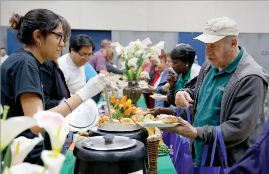  ?? Nikolas Samuels/ The Signal (See additional photos at signalscv.com) ?? People are served food at the Newhall Community Center during the annual Thanksgivi­ng Community Dinner on Monday. Some 600 people were expected to attend the meal, which was free to the public. Teenages with the center’s iTeens program and city staff...