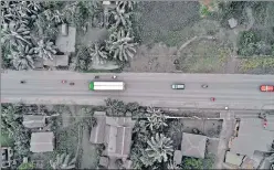  ?? AFP ?? Vehicles driving past ash-covered houses and vegetation in Juban town, Sorsogon province, after Bulusan volcano erupted. Ashfall hit at least seven villages in and near Juban at the foot of Bulusan where people were asked to stay indoors and wear masks. .