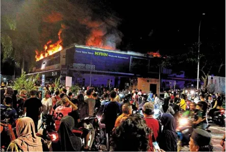  ?? Bernama ?? Chaotic scene: People watching as firefighte­rs work to extinguish the blaze at the hypermarke­t in Manjoi, Ipoh. —