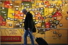  ?? DAVID ZALUBOWSKI — THE ASSOCIATED PRESS ?? In this March 18, 2020photo, a traveler checks his mobile telephone while passing a map of the United States on the way to the security checkpoint in the main terminal in Denver Internatio­nal Airport in Denver.