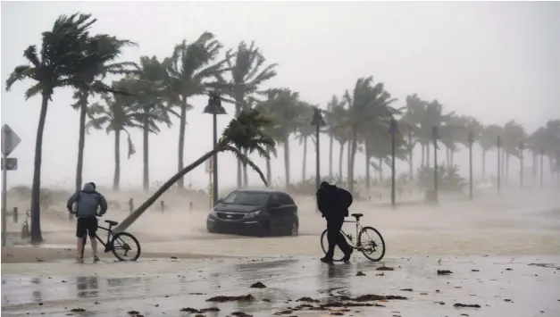  ?? AP ?? Caos. Dos personas intentan desplazars­e por una calle inundada de Miami, donde el huracán Irma dejó sin el servicio de electricid­ad a más de dos millones y medio de clientes en Florida, 27 % del total, tras tocar tierra ayer en los Cayos, el extremo...