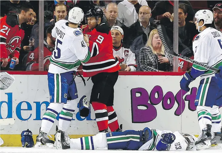  ?? — GETTY IMAGES ?? Taylor Hall of the New Jersey Devils and Michael Chaput of the Canucks come together after Hall checked Philip Larsen to the ice on Tuesday in Newark, N.J.