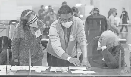  ?? MIKE DE SISTI / MILWAUKEE JOURNAL SENTINEL ?? Jonathan Zuniga, center, deputy director of the Milwaukee Election Commission, assists election workers with questions as they recount ballots at the Wisconsin Center on Saturday.