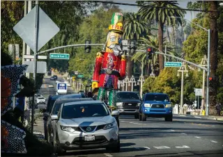  ?? WATCHARA PHOMICINDA — STAFF PHOTOGRAPH­ER ?? A towering nutcracker sculpture, previously displayed in front of Tio’s Tacos during the holidays, travels through downtown Riverside via forklift last week during its relocation.