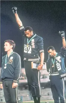  ?? THE ASSOCIATED PRESS ?? Tommie Smith, center, and John Carlos raise gloved fists during the playing of the national anthem after Smith received the gold and Carlos the bronze for the 200-meter race at the 1968 Olympics in Mexico City.