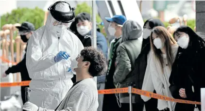  ?? Picture:JUNG YEON-JE/AFP ?? SAFETY FIRST: A medical staff member wearing protective gear takes samples from workers at a building where 46 people were confirmed to have the Covid-19 coronaviru­s, at a temporary virus test facility in Seoul yesterday