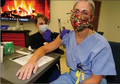  ?? (AP/David Zalubowski) ?? Rebecca Hong, a registered nurse and assistant nurse manager at Rose Medical Center in Denver, administer­s the covid-19 vaccine from Moderna to Dr. Kristi Keil, a urogynecol­ogist at the hospital, on Wednesday. Many employers are providing vaccinatio­ns for workers, but aren’t requiring them.