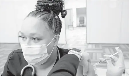  ??  ?? Respirator­y therapist Leigha McDaniels receives a COVID-19 vaccinatio­n Dec. 14 at a St. Louis hospital.