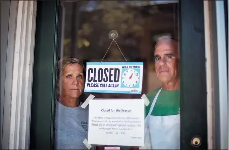  ?? DAVID GOLDMAN — THE ASSOCIATED PRESS ?? Steve, right, and Chris Brophy, husband and wife owners of Brickley’s Ice Cream, look out from the store they closed after teenage workers were harassed by customers who refused to wear a mask or socially distance, in Wakefield, R.I., July 29.