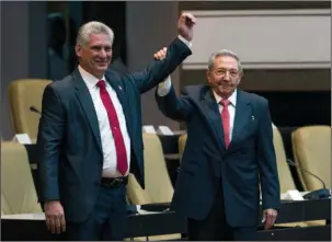 ?? The Associated Press ?? TRANSITION: Cuba’s new president Miguel Diaz-Canel, left, and former president Raul Castro, raise their arms after Diaz-Canel was elected as the island nation’s new president on Thursday at the National Assembly in Havana, Cuba. Castro left the...