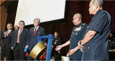  ??  ?? All smiles:
Dr Ahmad Zahid (centre) hitting a gong during his visit to Maktab PDRM in Kuala Lumpur. Looking on are (from left) Alwi, Nur Jazlan, Mohamad Fuzi and Noor Rashid.