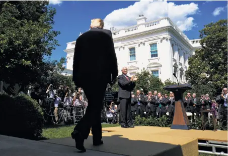  ?? T.J. Kirkpatric­k / Bloomberg ?? President Trump receives applause as he prepares to deliver his speech on the Paris accord at the White House Rose Garden.