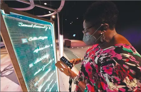  ?? (AP/Rogelio V. Solis) ?? Pamela D.C. Junior, director of the Two Mississipp­i Museums in Jackson, Miss., searches for a specific cold case selection Aug. 27 at the PBS Frontline’s traveling augmented-reality exhibit “Un(re)solved” in the museum’s special exhibit room.