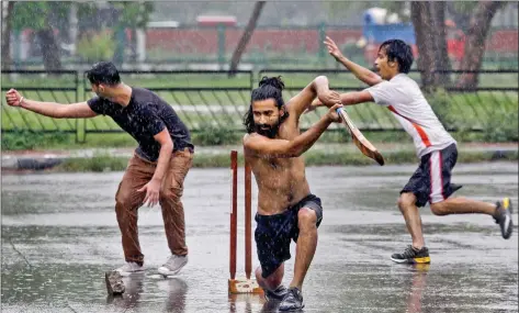  ?? REUTERS ?? Boys play cricket at a parking lot as it rains in Chandigarh on Tuesday.