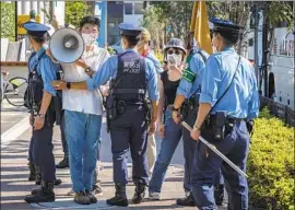  ?? Yuichi Yamazaki Getty Images ?? POLICE surround anti-Olympics protesters during an event celebratin­g the torch relay on Monday in Tokyo. Some public relay events had to be canceled.