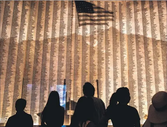  ?? Photograph­s by Kent Nishimura Los Angeles Times ?? VISITORS LOOK at a display Saturday at the Manzanar National Historic Site naming people of Japanese ancestry whom the U.S. incarcerat­ed during World War II.