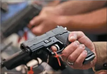  ?? AP PHOTO/JULIE JACOBSON ?? In this file photo, a convention attendee handles a Sig Sauer P220 .45 caliber semiautoma­tic pistol