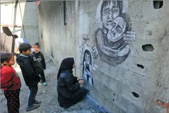  ?? MOHAMMED TALATENE / ASSOCIATED PRESS ?? Palestinia­n artist Menna Hamouda draws with charcoal on the walls of a school in the central Gazan city of Deir al-Balah on Wednesday.