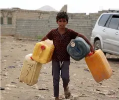  ?? — AFP photo ?? A Yemeni child carries empty jerrycans amid continuing wide spread disruption of water supply in the impoverish­ed coastal village on the outskirts of the Yemeni port city of Hodeidah.