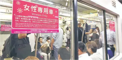  ??  ?? A poster informing commuters of a women’s-only carriage is displayed on a subway train in Tokyo. In Japan, where train travel can often be a perilous ordeal for women, an insurance company is reporting a sudden run on a policy that protects men falsely...