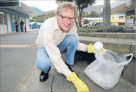  ??  ?? On a mission: Peter Turney uses supermarke­t bags and rubber gloves to collect rubbish around Tawa’s streets.