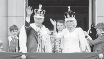  ?? MATT CROSSICK/EMPICS PA Images/Alamy Images/Sipa USA ?? King Charles III and Queen Camilla wave to the crowd as they make their first public appearance on the balcony of Buckingham Palace, following the coronation ceremony Saturday in London.