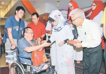  ??  ?? Fatimah (front row, second from right) handing an angpow to one of the recipients of the ‘Sejambak Kasih’ programme at a leading hotel here Friday. — Photo by Chimon Upon