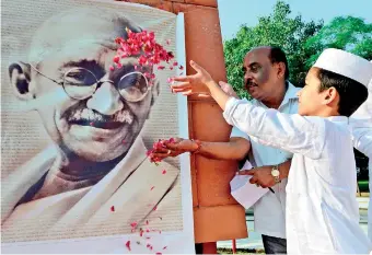  ??  ?? A Muslim boy showers rose petals on a portrait of Indian independen­ce icon Mahatma Gandhi during a tribute to mark his 150th birth anniversar­y in Amritsar on October 2, 2019. (Photo by NARINDER NANU / AFP)
