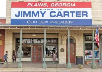  ?? ARVIN TEMKAR / ATLANTA JOURNAL-CONSTITUTI­ON ?? On Sunday, a person walks past stores on Main Street in Plains, Ga.