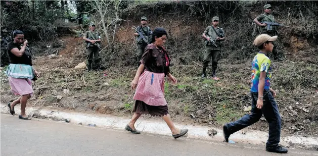  ?? JOHAN ORDONEZ/AFP/ Getty Image s files ?? Locals walk by an army patrol in southeaste­rn Guatemala in May, days after security forces clashed with opponents of a Canadian-owned gold and silver mine project.