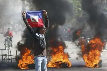  ?? Odelyn Joseph/Associated Press ?? A demonstrat­or holds up an Haitian flag during protests Friday demanding the resignatio­n of Prime Minister Ariel Henry in Port-au-Prince, Haiti. Five people died.